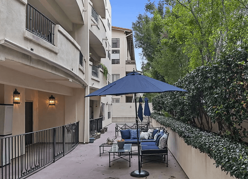 a patio with a blue umbrella and chairs on it